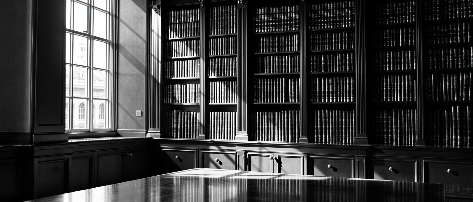 Law library of shelved bound volumes with side light coming through a high
        window.